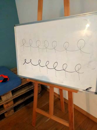 Deux lignes de boucles cursives tracées sur un grand tableau blanc.